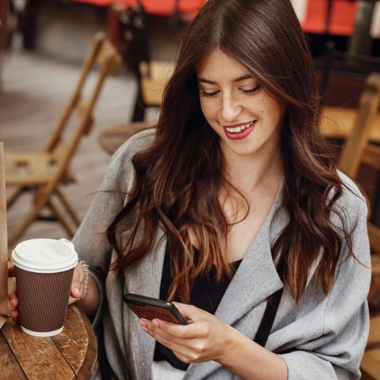 gorgeous-young-woman-holding-phone-and-smiling-wit-SBKQDZ9.jpg